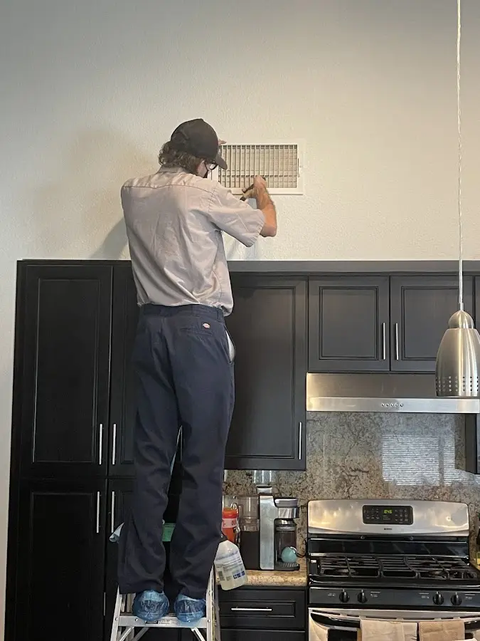 Technician inspecting an air vent during HVAC service in McAllen